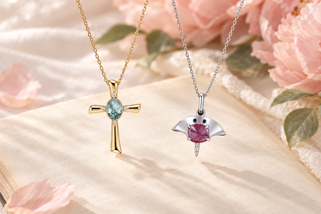 Moss agate cross and pink sapphire manta ray necklaces on an open book