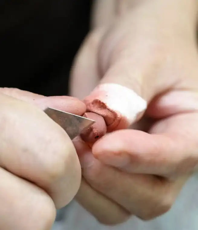 Artisan carving a black aromatic bead by hand